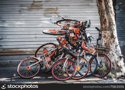 Pile of broken electric bikes on the sidewalk, Hangzhou, China. Infrastructure and regulations were not prepared to handle a sudden flood of millions of shared bicycles.. Pile of electric bikes on the sidewalk, Hangzhou