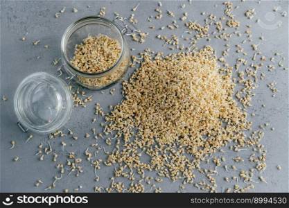 Pile of buckwheat sprouts in glass jar over grey background. Buckwheat grains. Vitamins and healthy eating concept. Tasty breakfast