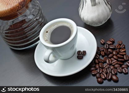 pile of coffee beans and a cup on a gray table