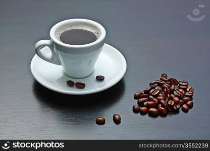 pile of coffee beans and a cup on a gray table