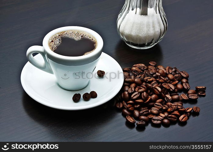 pile of coffee beans and a cup on a gray table