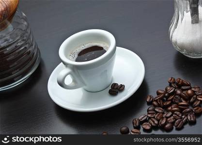 pile of coffee beans and a cup on a gray table