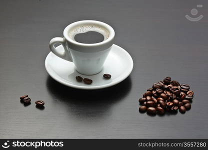 pile of coffee beans and a cup on a gray table