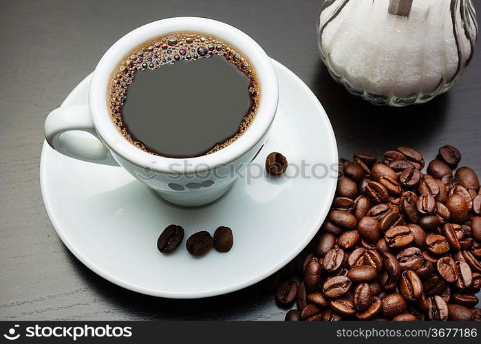 pile of coffee beans and a cup on a gray table