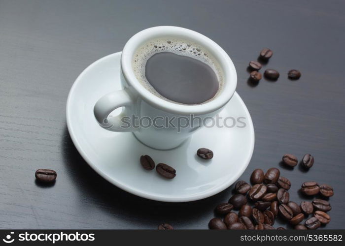 pile of coffee beans and a cup on a gray table