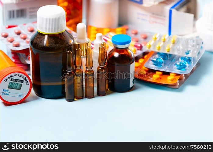 Pile of colorful medical pills and bottles border on blue background with copy space. Drug and antibiotics prescription for treatment medication.. Pile of pills