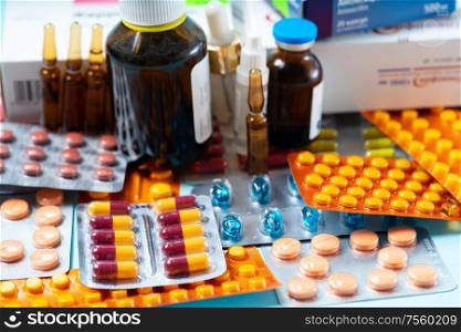 Pile of colorful medical pills and bottles on blue background. Druga and antibiotic prescription for treatment medication. Pile of pills
