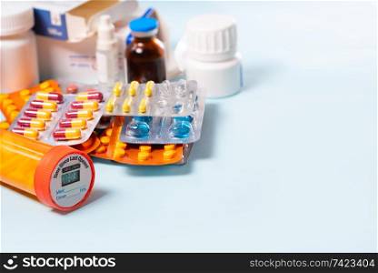 Pile of colorful medical pills and bottles on blue background with copy space. Drug and antibiotics prescription for treatment medication.. Pile of pills