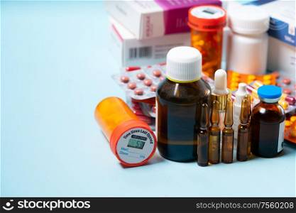 Pile of colorful medical pills and bottles on plain blue background with copy space. Drug and antibiotics prescription for treatment medication.. Pile of pills