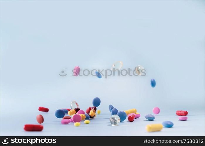 Pile of colorful medical pills falling on blue background. Medical pharmacy concept. Antibiotic drug resistance. Pharmaceutical industry. Antimicrobial drug market.. Pile of pills
