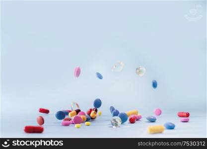 Pile of colorful medical pills falling on blue background. Medical pharmacy concept. Antibiotic drug resistance. Pharmaceutical industry. Antimicrobial drug market.. Pile of pills