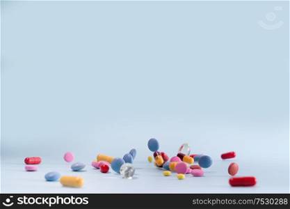 Pile of colorful medical pills on blue background, blue backdrop with copy space. Pile of pills
