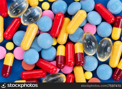 Pile of colorful medical pills on blue background. Pile of pills