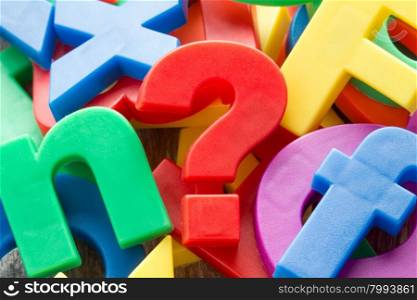 Pile of colorful plastic letters with red question mark