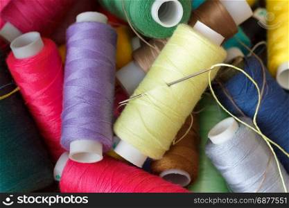 Pile of coloured bobbins of thread. Bobbins with threads of different colors, close-up