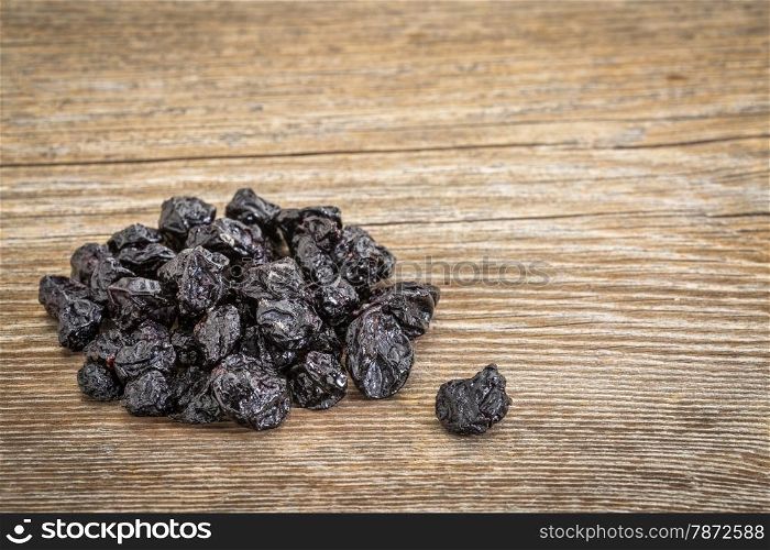 pile of dried blueberry fruit on grained grunge wood background