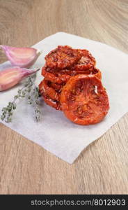 pile of dried tomatoes stacked on a baking paper with cumin and garlic