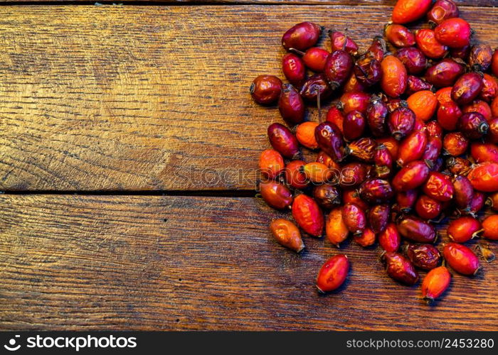 Pile of dry rose hips on a wooden board.