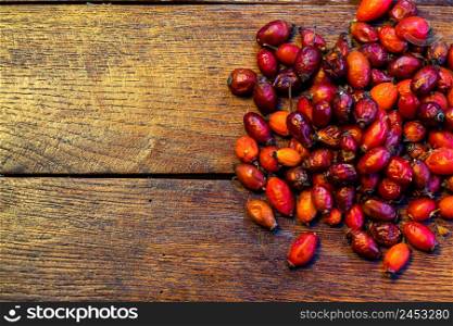Pile of dry rose hips on a wooden board.