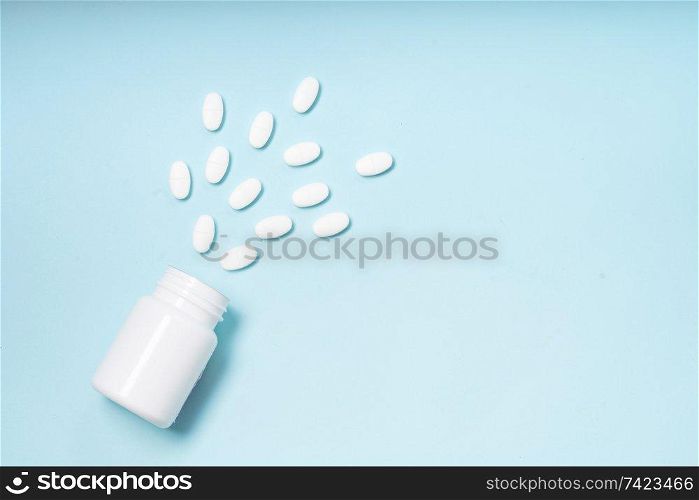 Pile of falling medical pills and bottle on blue background. Pile of pills