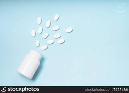 Pile of falling medical pills and bottle on blue background. Pile of pills