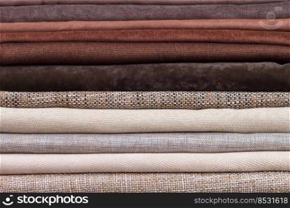 Pile of folded colorful textile. Heap of cloth brown and beige color fabric. Pile of folded textile