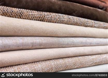 Pile of folded colorful textile. Heap of cloth brown and beige color fabric. Pile of folded textile