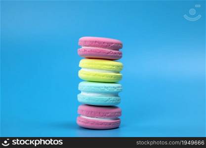 Pile of fresh baked colorful French macaroons on blue background , copy space banner. dessert,cookie,cake concept space for text. Pile of fresh baked colorful French macaroons on blue background , copy space banner. dessert,cookie,cake concept