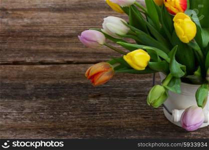 pile of fresh muticolored tulips on wooden table