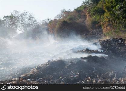pile of garbage burning white smoke. The air pollution.