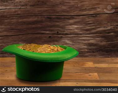 Pile of gold coins inside green hat St Patricks Day. Treasure of pure gold coins inside a green velvet hat on wooden table to celebrate luck on St Patrick&rsquo;s Day of March 17th. Pile of gold coins inside green hat St Patricks Day
