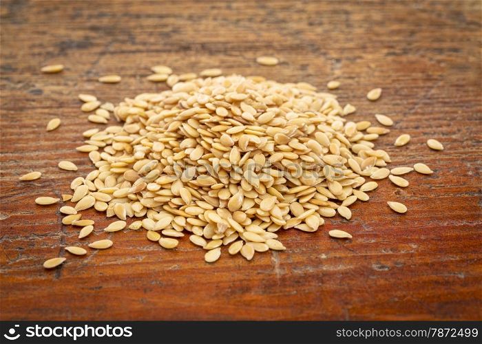 pile of gold flax seeds against a grunge wood background