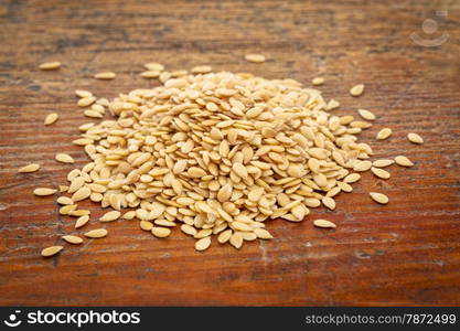 pile of gold flax seeds against a grunge wood background