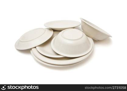 Pile of heaped plain beige dinner plates, soup plates and saucers isolated