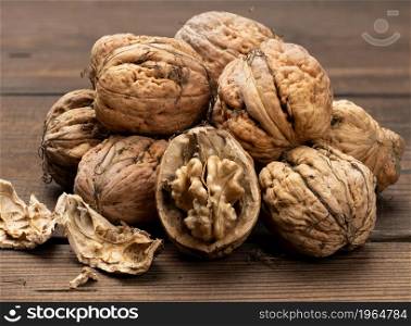 pile of inshell walnuts on a brown wooden table, autumn harvest, close up