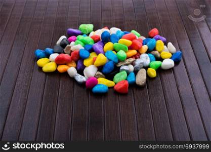 Pile of little colorful pebbles on wooden background