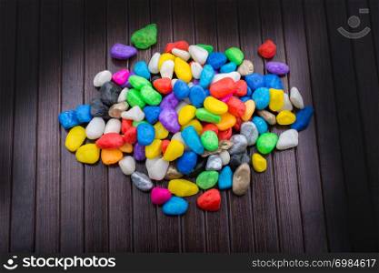 Pile of little colorful pebbles on wooden background