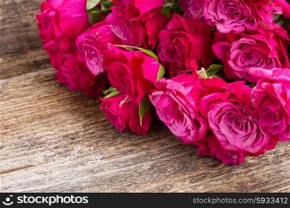 pile of mauve fresh small fresh roses on wooden table