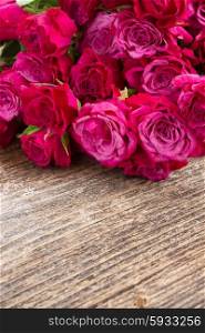 pile of mauvesmall fresh roses on wooden background