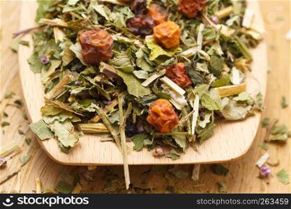 Pile of mixed natural medical dried herbs leaves and fruits on wooden spoon. . Pile of dry herb leaves and fruits on wooden spoon