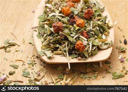 Pile of mixed natural medical dried herbs leaves and fruits on wooden spoon. . Pile of dry herb leaves and fruits on wooden spoon