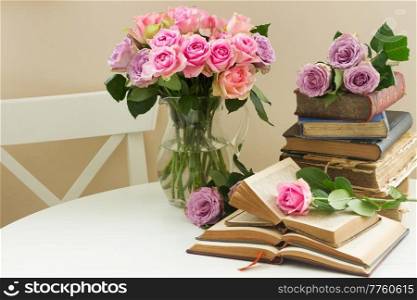 Pile of old books with bouqet of  rose flowers. Old books with rose flower