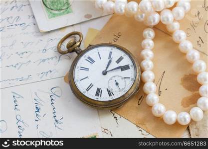 pile of old letters  with antique  clock and pearls