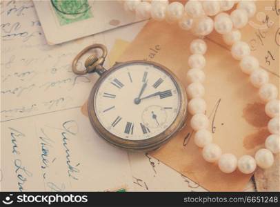 pile of old letters  with antique  clock and pearls, retro toned. old mail  with clock