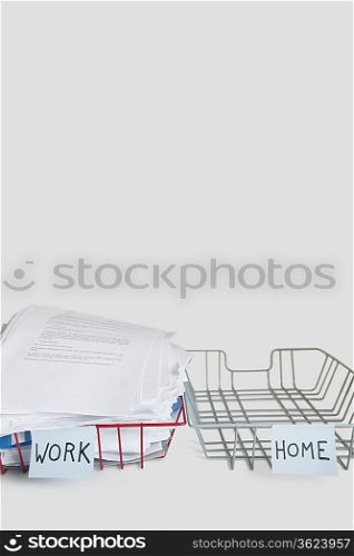 Pile of papers in work tray with empty home platter over white background