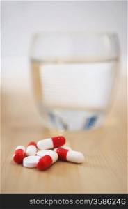 Pile of pills and glass of water on table close-up