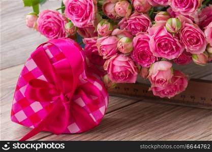 pile  of  pink small fresh  roses and heart box  on wooden background