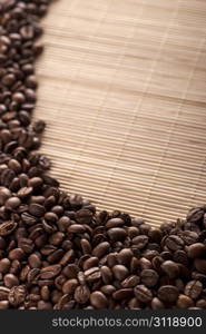 pile of roasted brown coffee beans on bamboo background