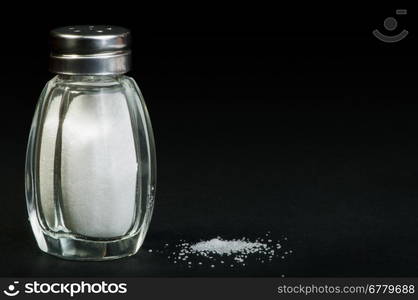 Pile of spilled salt and saltshaker black isolated