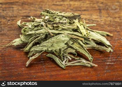 pile of stevia dried leaves against grunge wood - natural sweetener, sugar substitute